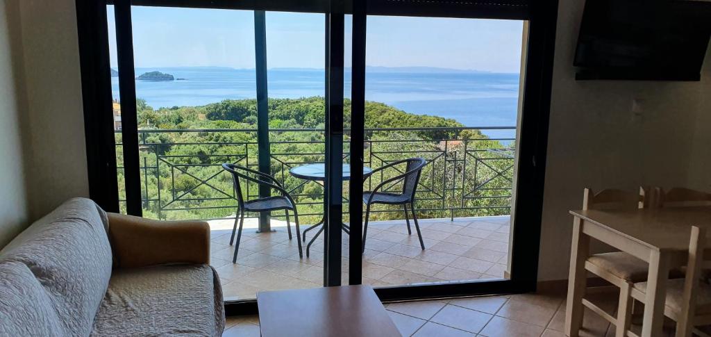 a living room with a view of the ocean from a balcony at Sivota Apartments in Syvota