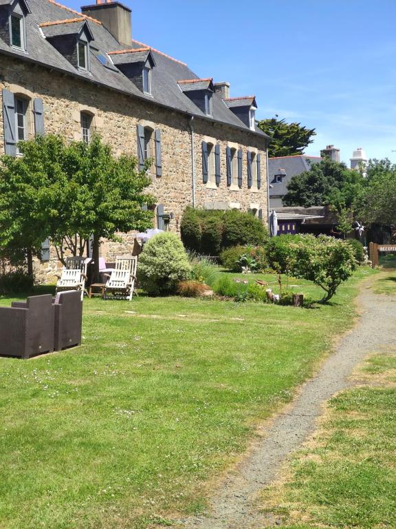 un edificio de ladrillo con sillas y un patio de césped en Appart'hotel Maison Saint Michel en Paimpol