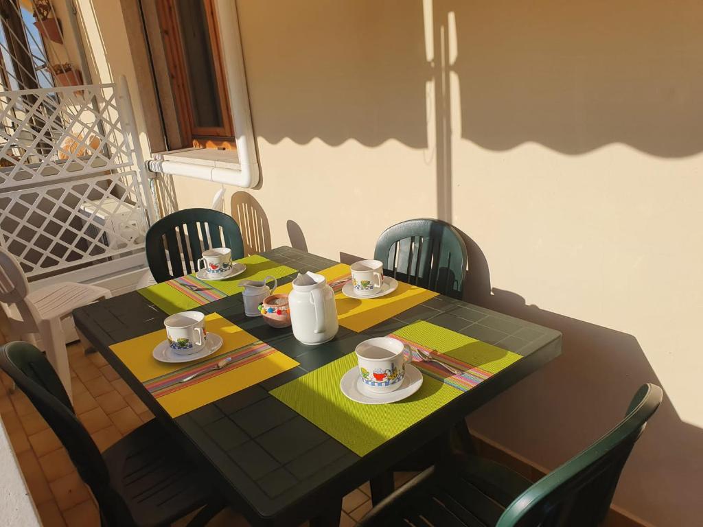 einen Tisch mit Stühlen und einen Tisch mit Tassen und Untertassen in der Unterkunft Casa Ameria in Cecina