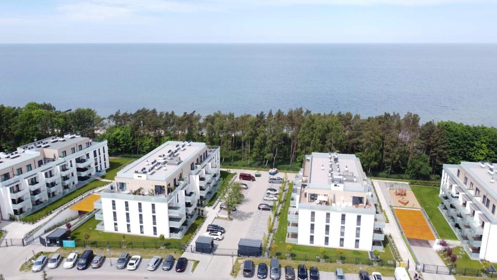 an aerial view of three white buildings next to the ocean at Apartament Tęcza in Rewal