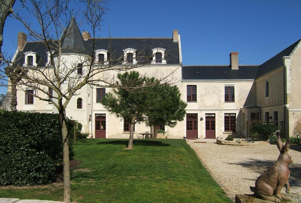 uma grande casa branca com uma estátua em frente em Gites Aubelle - La Maison Aubelle em Montreuil-Bellay