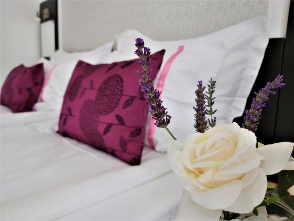 Una cama con almohadas moradas y blancas y un jarrón con flores en Casa Eladi, en Eforie Sud