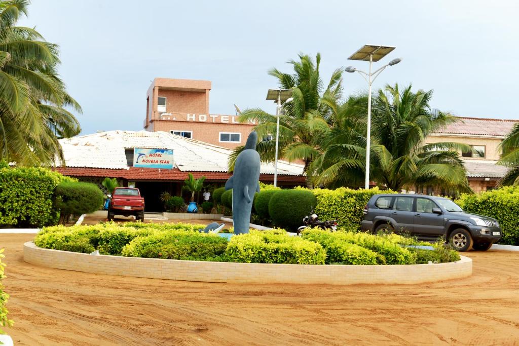 una estatua de un delfín delante de un edificio en Hotel Novela Star, en Lomé