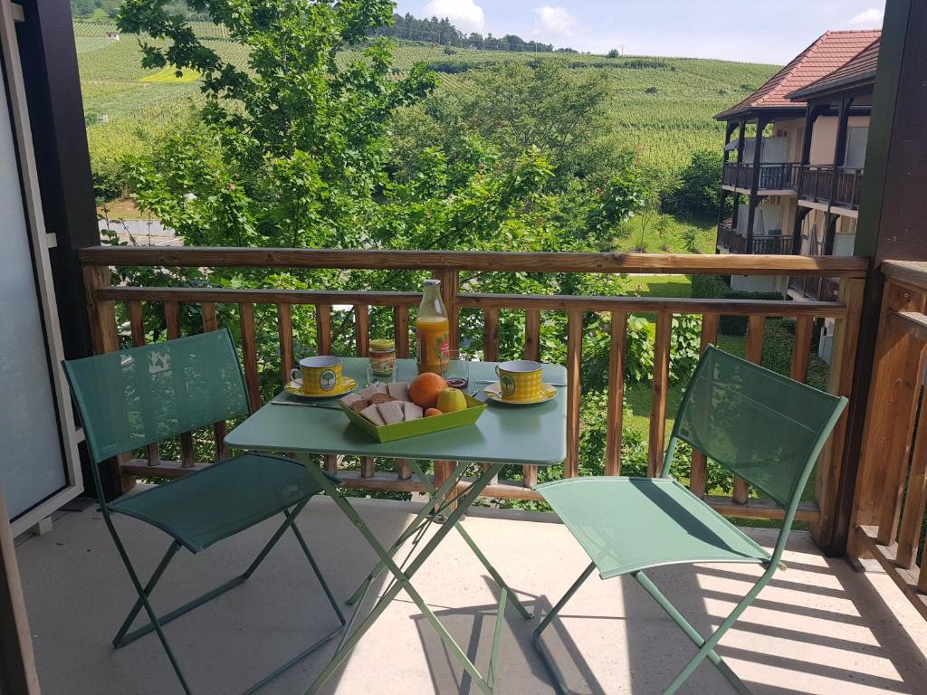 a table with a bowl of fruit on a balcony at Le Petit Nid in Bergheim