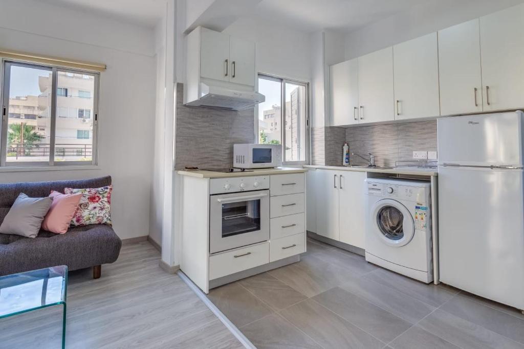 a kitchen with white cabinets and a washer and dryer at Downtown Larnaca in Larnaka
