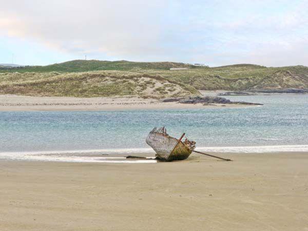 an old boat sitting on the sand on a beach at Apartment No. 3 Bunbeg in Bunbeg