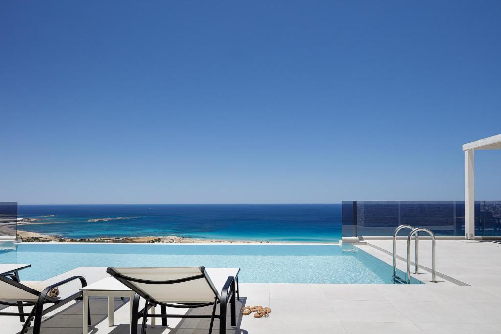 a pool with chairs and the ocean in the background at Falasarna village in Falasarna