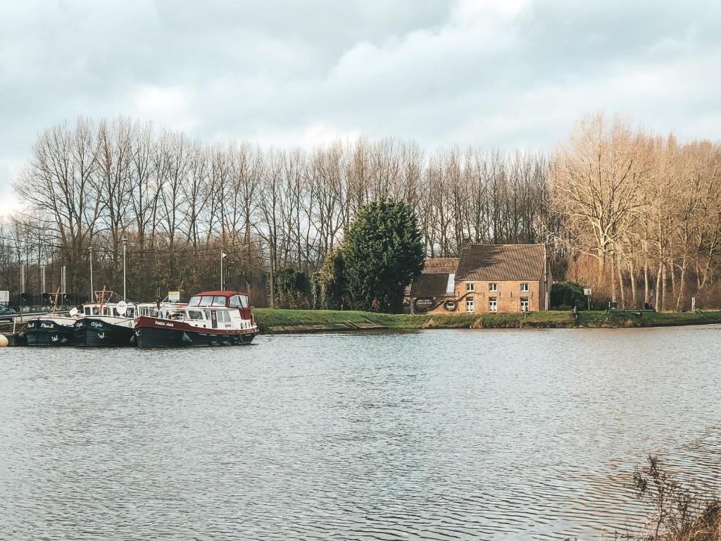 een boot is aangemeerd op het water naast een huis bij Hoeve Westdijk in Oostkamp