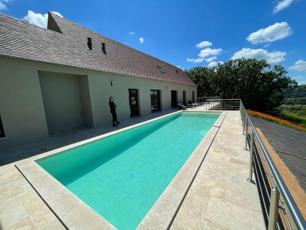 a man standing next to a swimming pool next to a building at Gîte du point de vue in Autoire
