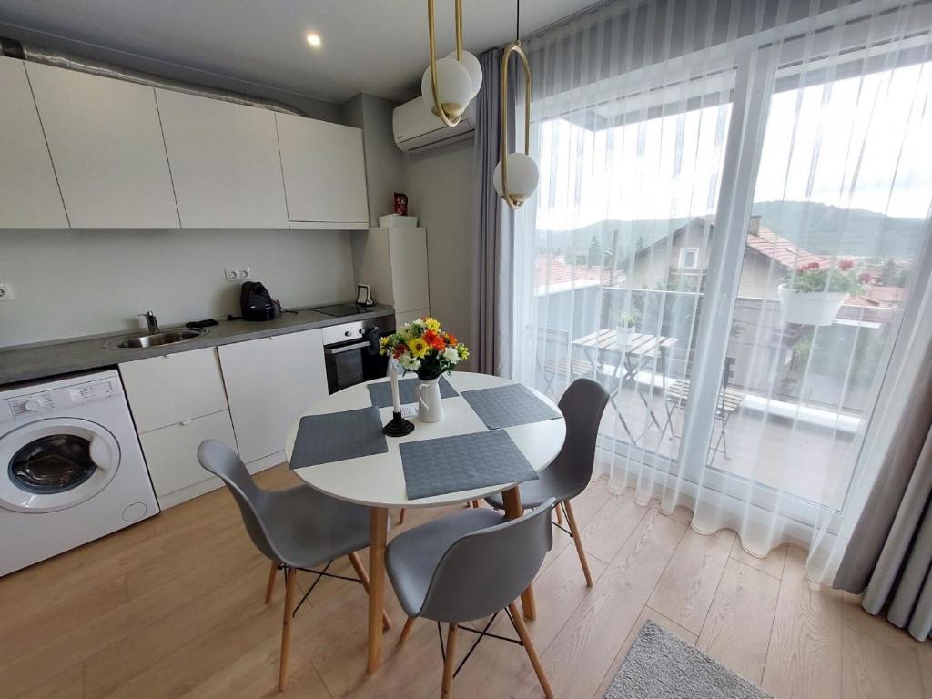 uma cozinha com uma mesa e cadeiras numa cozinha em TheHouse - Apartment Kamenitza em Velingrad