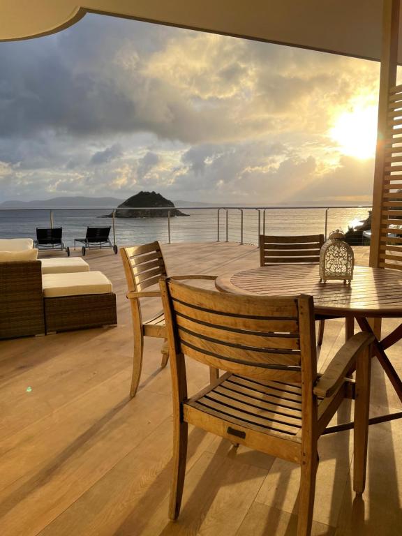 una mesa de madera y sillas en una terraza con vistas al océano en PUNTA dei BARBARI #MAESTRALE #LIBECCIO #TRAMONTANA, en Cavo