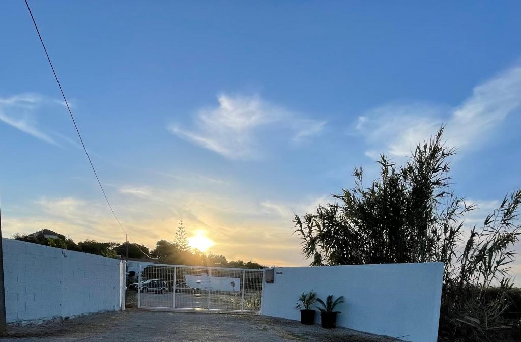 un coucher de soleil derrière une clôture blanche avec un portail dans l'établissement Kerart Lima, à Armação de Pêra