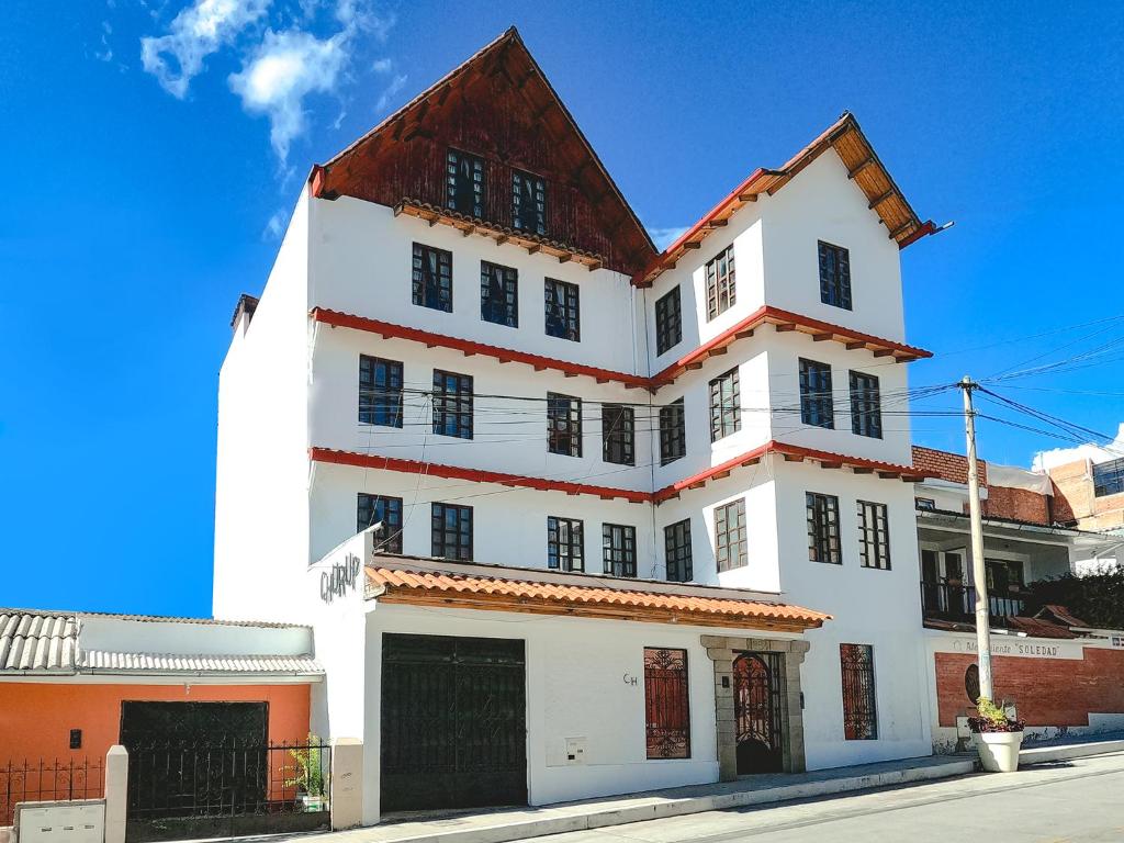 a white building with a red roof on a street at Hotel Churup in Huaraz