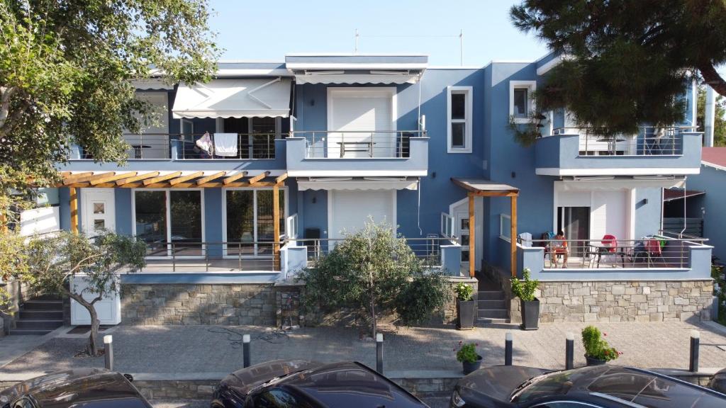 a blue house with cars parked in front of it at Isalos Suites in Néa Péramos