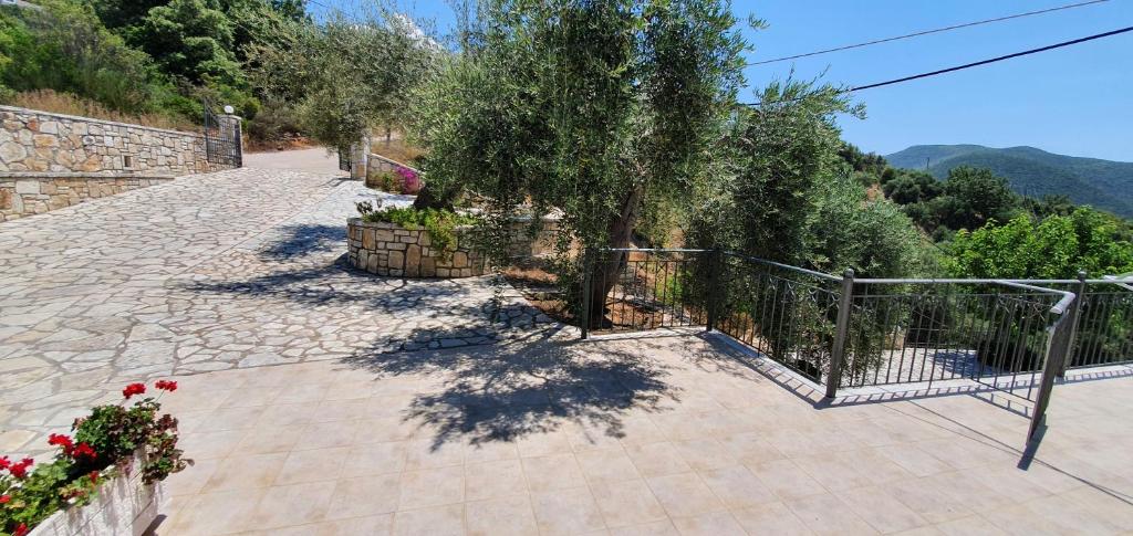 a stone walkway with a fence and a tree at Sivota Apartments in Syvota