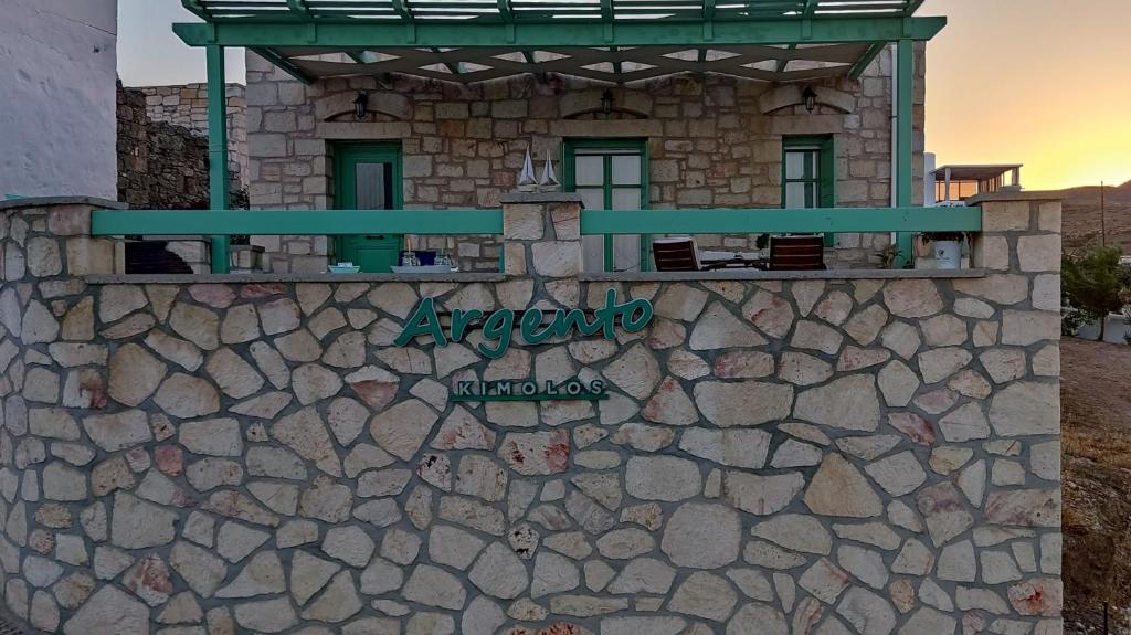 a building on a stone wall with a sign on it at Argento in Kimolos