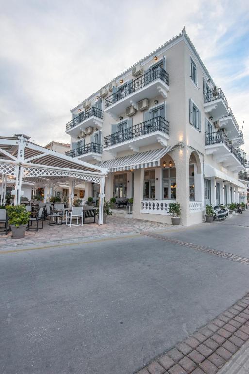 a white building with tables and chairs on the street at Klimis Hotel in Spetses