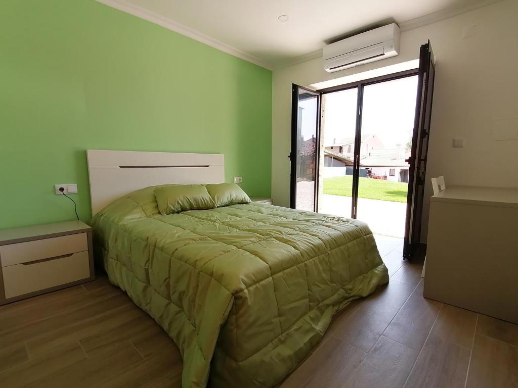 Un dormitorio con una cama con un edredón verde. en Alojamentos Martinho, en Quintas