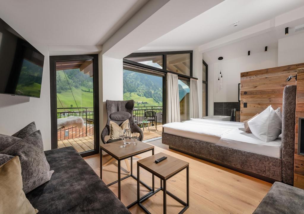 a bedroom with a bed and a living room at Hotel Alpenhof in Grossarl