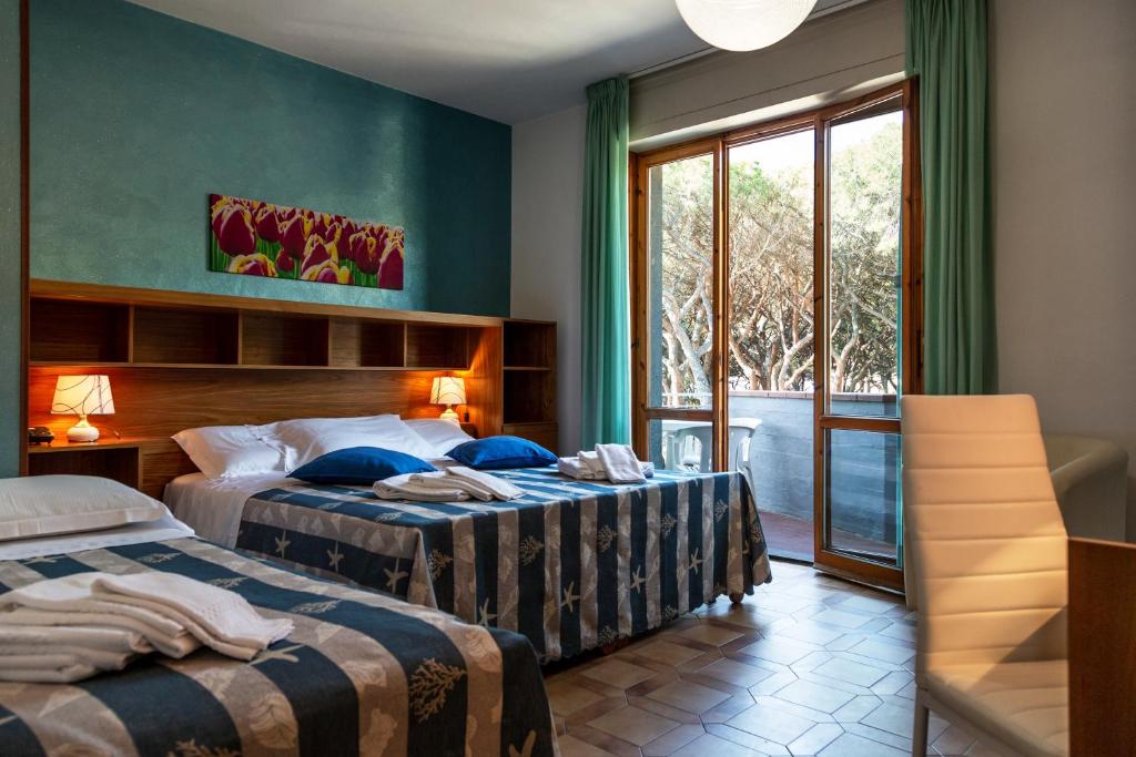 Habitación de hotel con 2 camas y ventana en Hotel Parco dei Pini, en Follonica