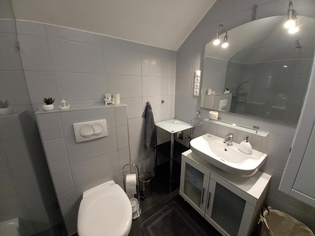 łazienka z toaletą, umywalką i lustrem w obiekcie Laura Luxury Apartman Gyenesdiás w Gyenesdiás