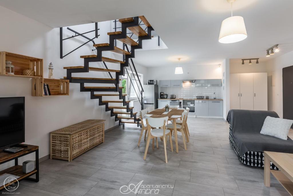 a living room with a staircase and a table and chairs at Apartamenty Ambra in Dębina