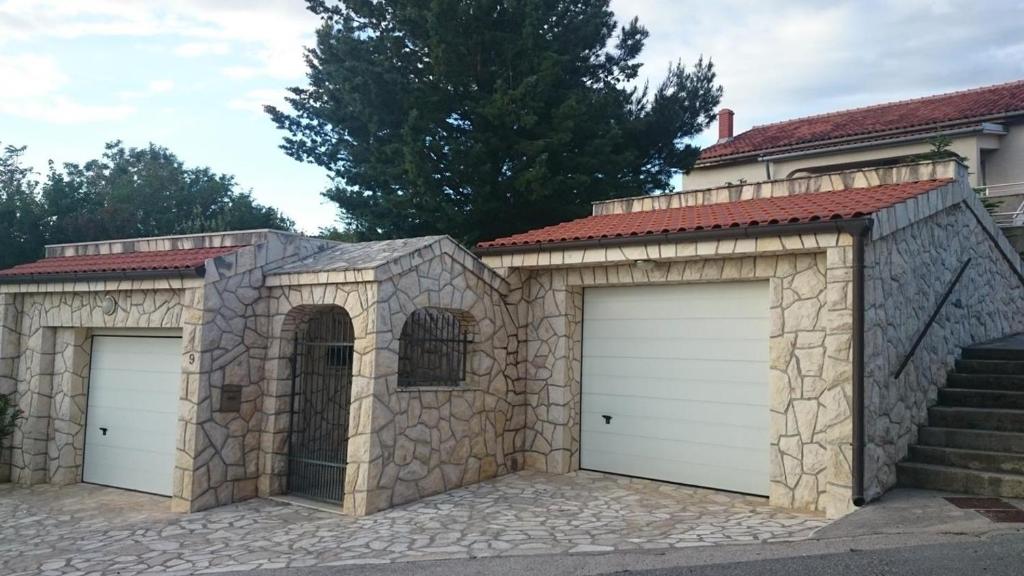 two garage doors in a stone building with stairs at Apartmani Lea in Jadranovo