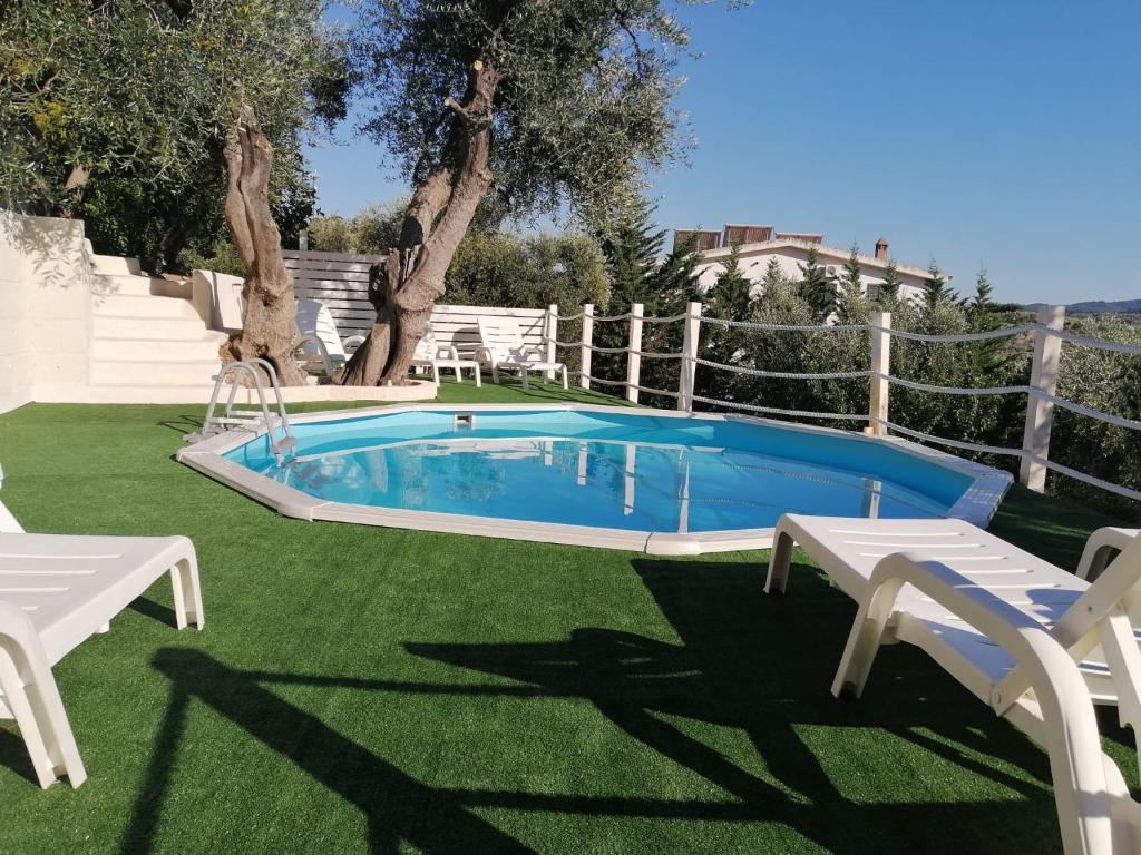 a swimming pool in a yard with two white chairs at B&B Borgo Degli Ulivi in Vieste