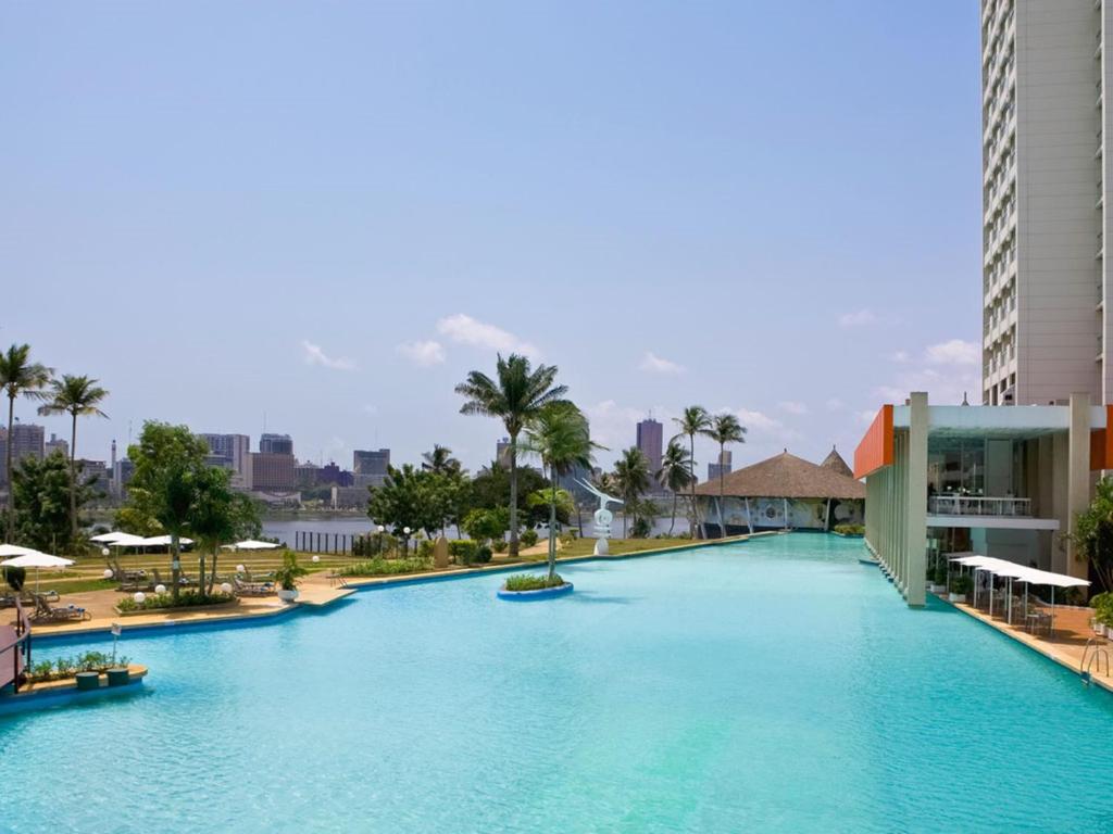 - une grande piscine d'eau bleue dans un complexe dans l'établissement Sofitel Abidjan Hotel Ivoire, à Abidjan