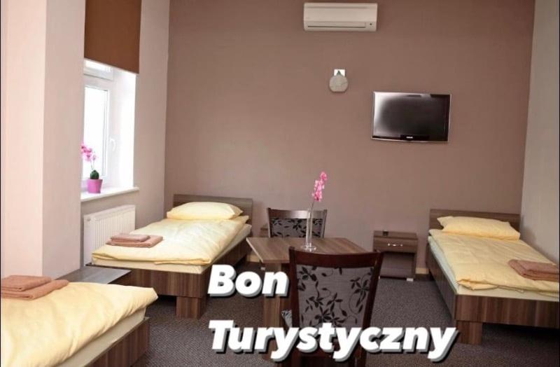 a room with two beds and a table and a tv at Noclegi Gemini Dom in Elblag