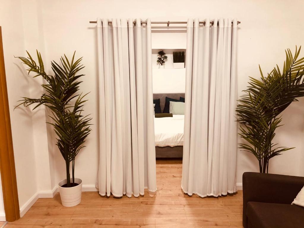 a bedroom with white curtains and two potted plants at Villa Tlv רחוב הירקון 27 תל אביב in Tel Aviv
