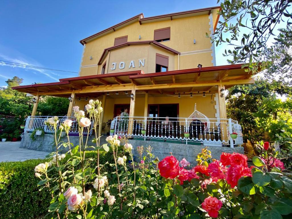 a building with a balcony and flowers in front of it at Joan Guesthouse in Përmet