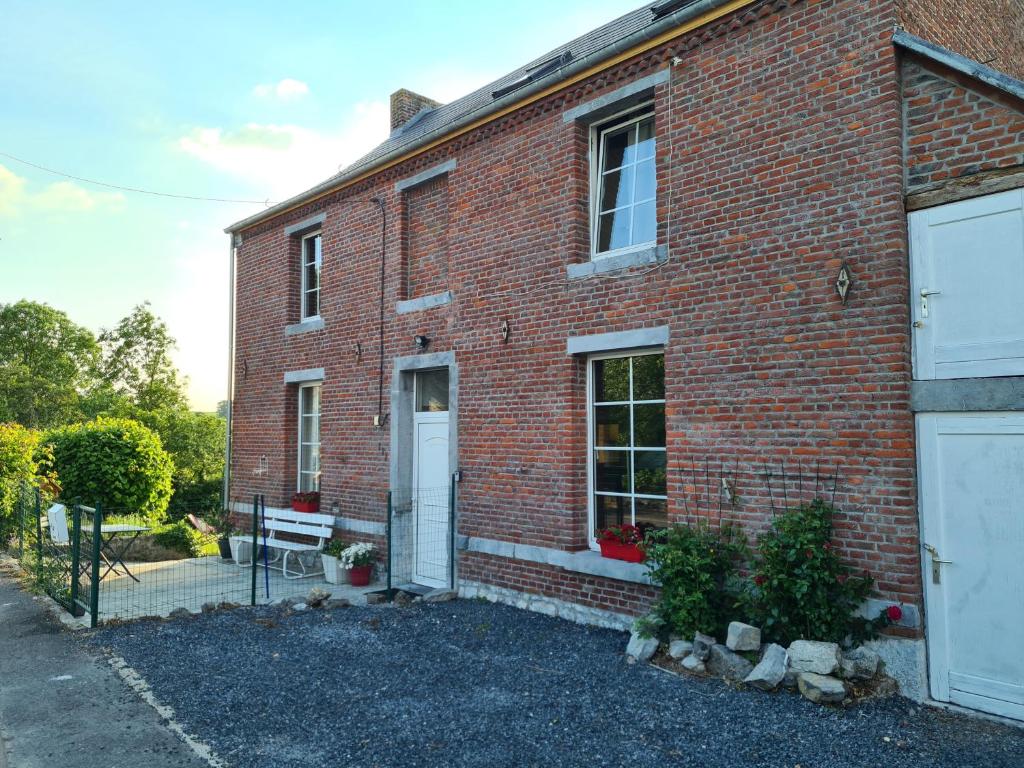 un edificio de ladrillo rojo con puerta blanca en Maison de campagne avec superbe vue panoramique!, en Bousignies-sur-Roc