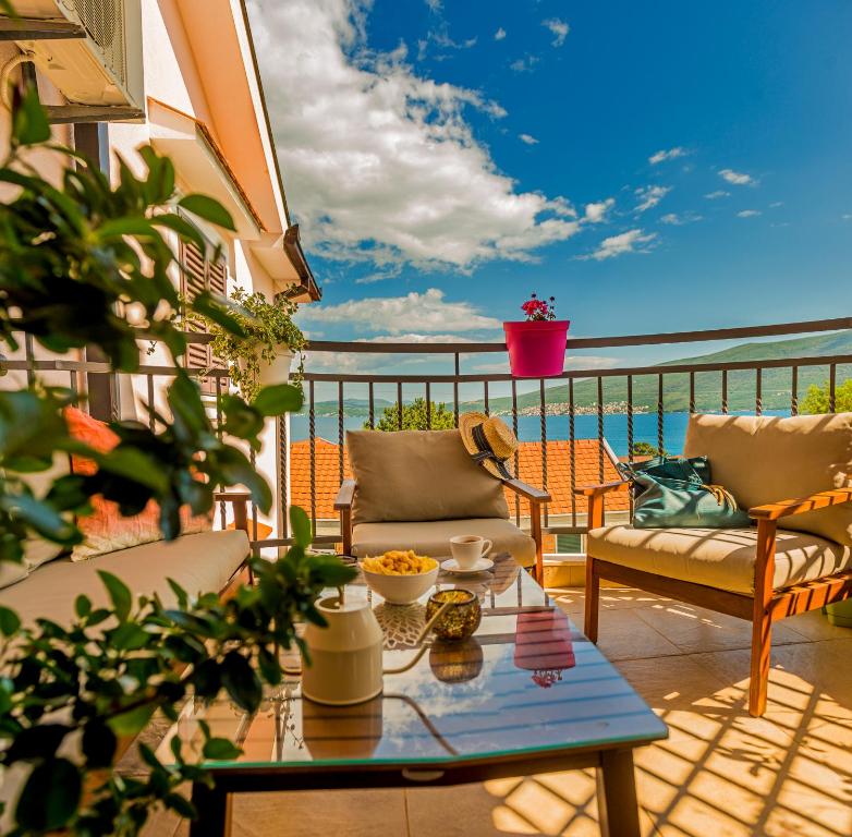 a patio with a table and chairs on a balcony at Cicciobello Lux Apartment Baošići with stunning sea view in Baošići