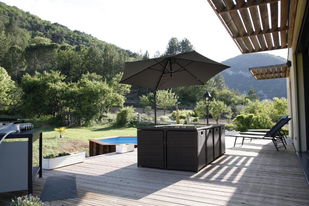 eine Terrasse mit einem Sonnenschirm, einem Tisch und einem Pool in der Unterkunft Villa en Campagne Provençale avec piscine in Curnier