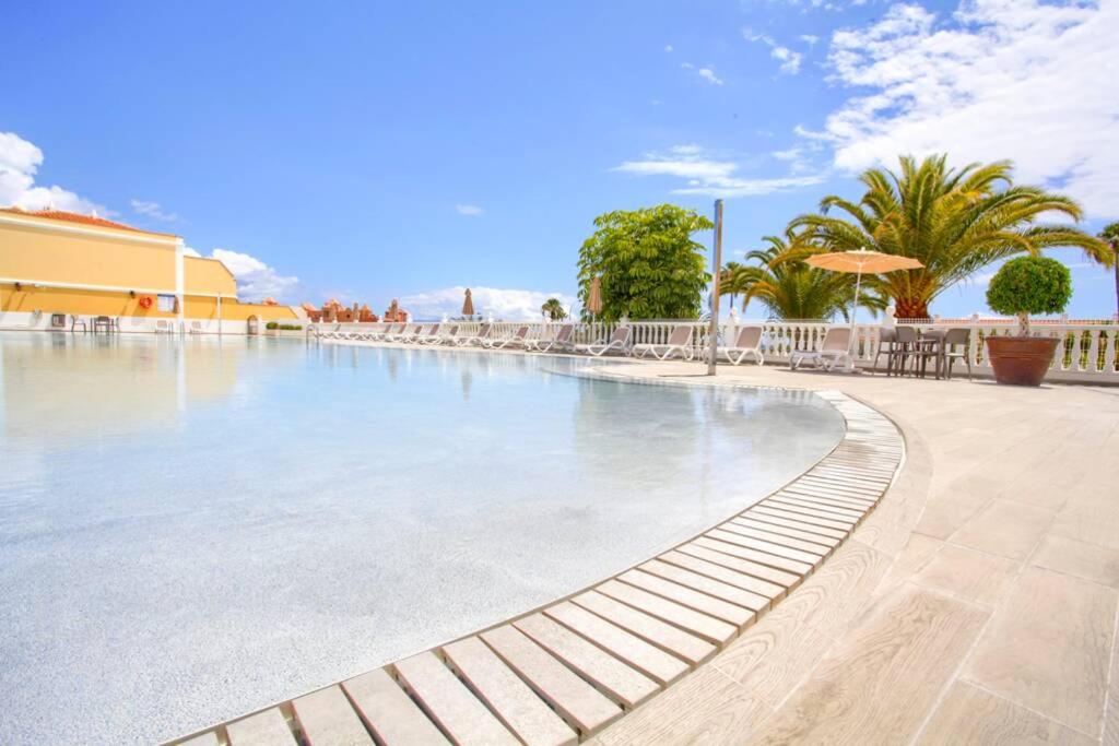 a swimming pool at a resort with tables and umbrellas at El Veril 84 Bahia del Duque in Adeje