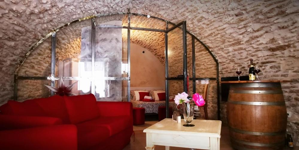 a living room with a red couch and a barrel at Chambre d hote de charme avec plein d authenticité du 13 ème siècle in Châteauneuf-du-Pape