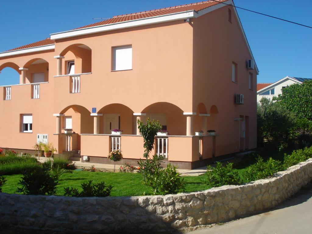a large building with a stone wall in front of it at Apartments Luna in Sukošan