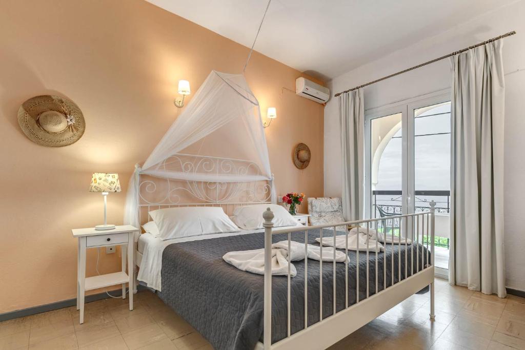 a bedroom with a canopy bed and a balcony at Eros Beach Hotel in Benitses