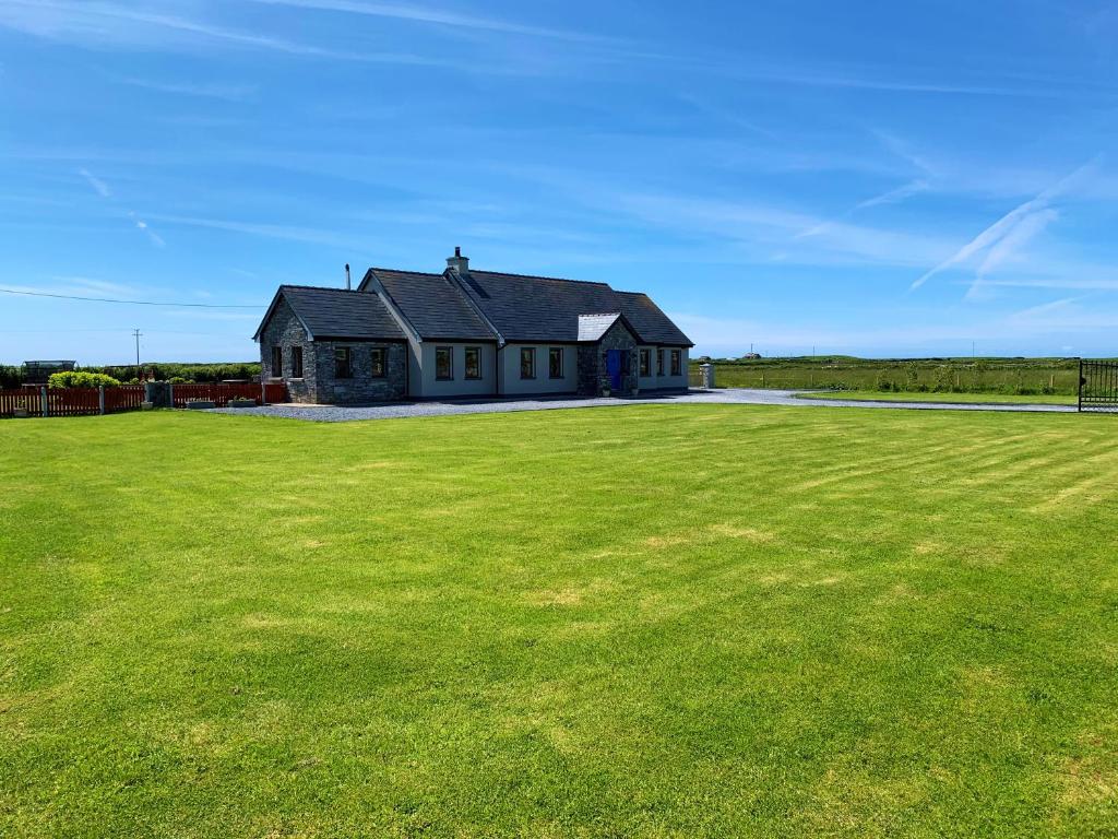 a house with a large green field in front of it at Wild Atlantic Breeze Guesthouse in Doolin