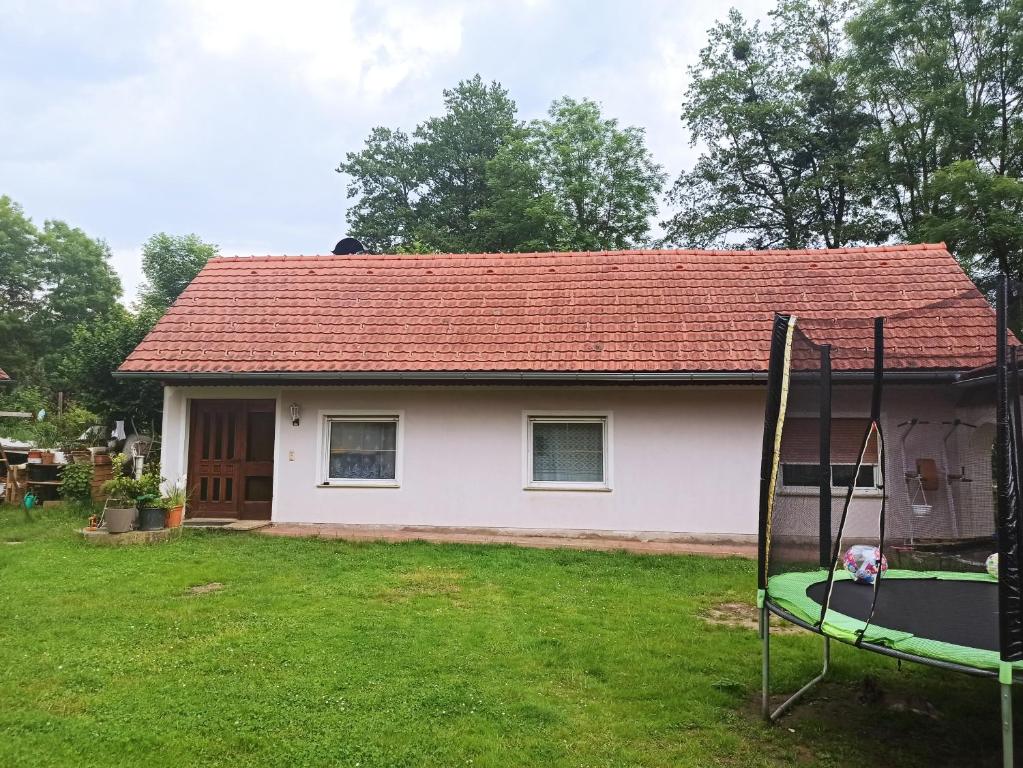 ein kleines weißes Haus mit einem Spielplatz im Hof in der Unterkunft Haus Jennifer in Hart bei Graz