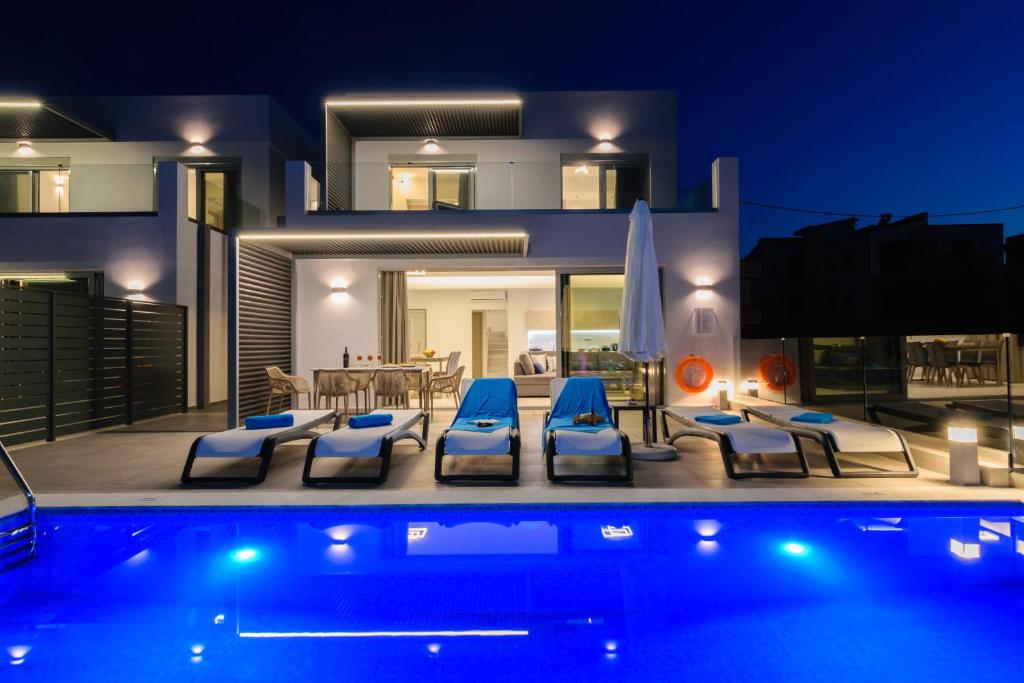 a villa with a swimming pool in front of a house at Katakis LuxuryVillas in Chania Town