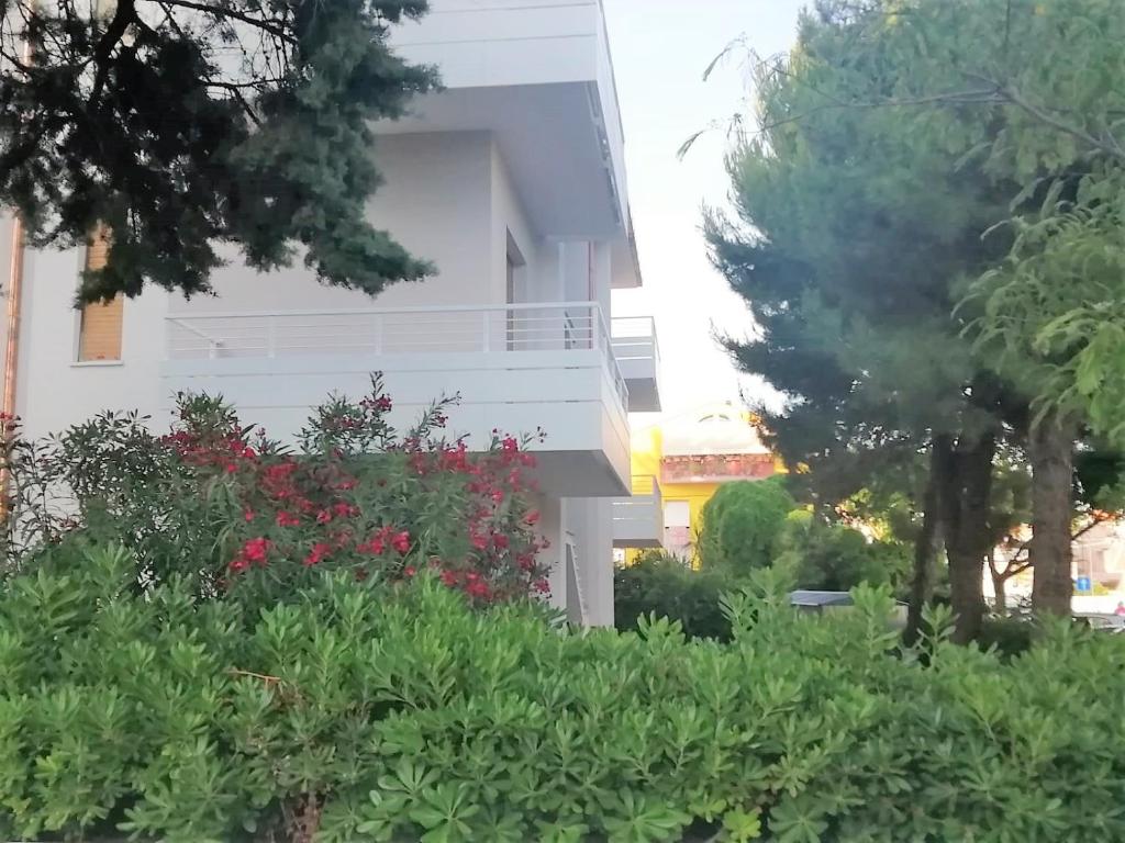 een wit gebouw met rode bloemen in een tuin bij via Ancona a 50mt dal mare in Marcelli