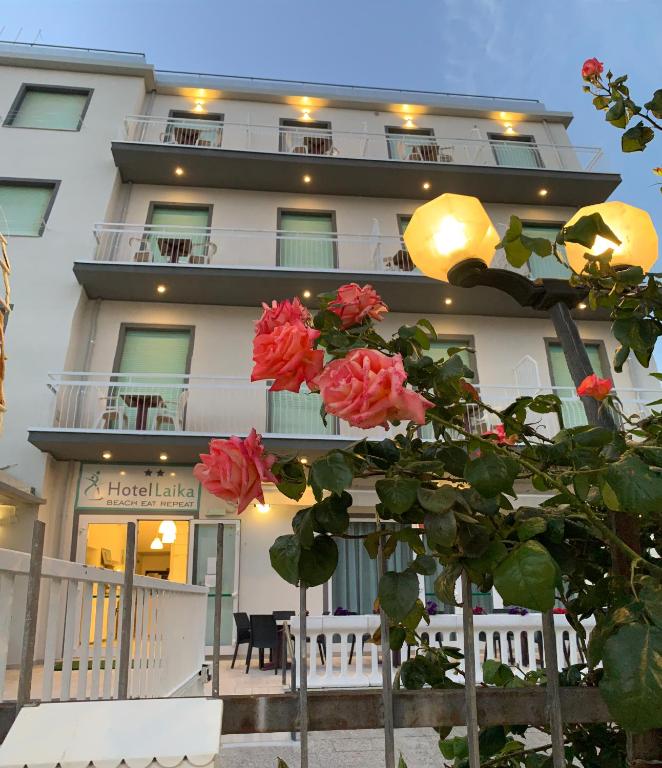 Um edifício com rosas vermelhas à frente. em Hotel Laika em Rimini