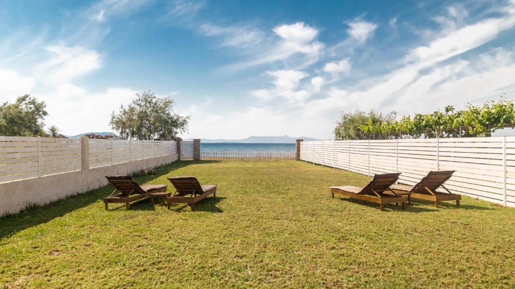 a group of chairs sitting on the grass near a fence at Terracotta beach house in Lefkímmi