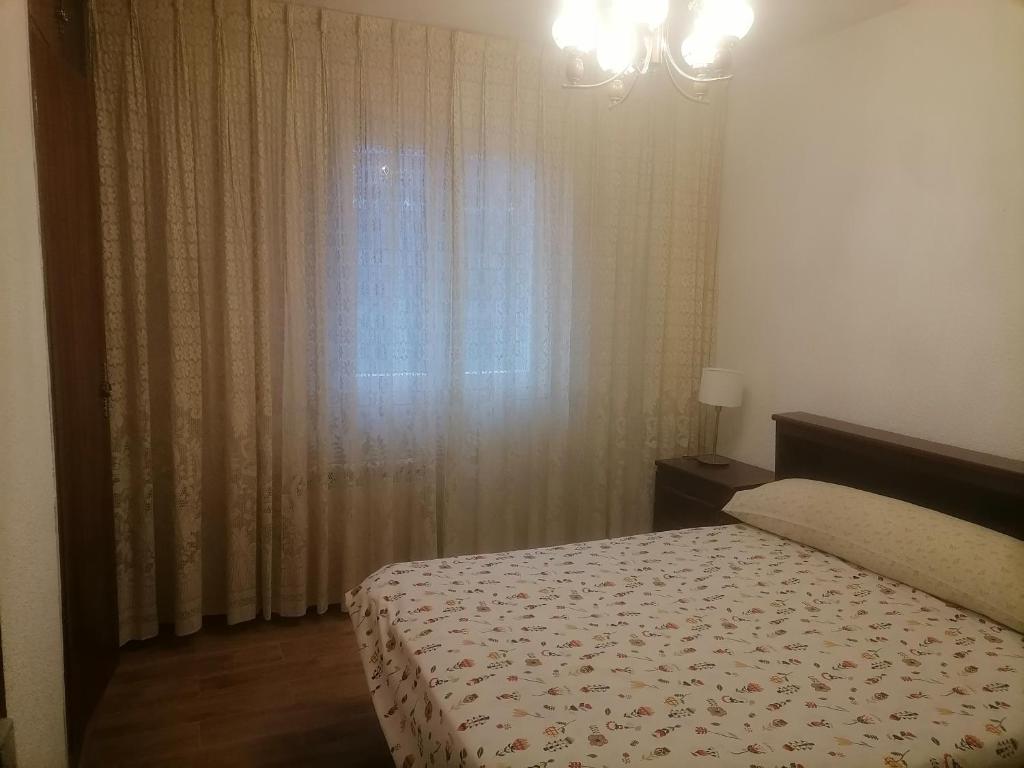 1 dormitorio con 1 cama y una ventana con cortinas en Apartamento vega de arriba, en Mieres