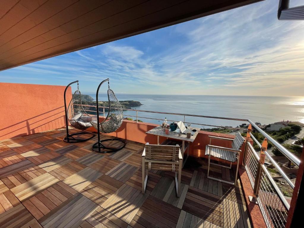 balcone con tavolo, sedie e vista sull'oceano di Appartement avec vue exceptionnelle sur mer a Cerbère
