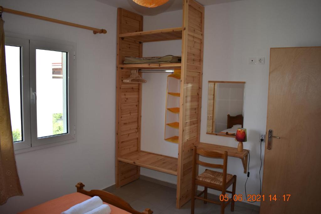 a room with a wooden closet with a mirror and a chair at Orange Tree Garden in Pefkochori