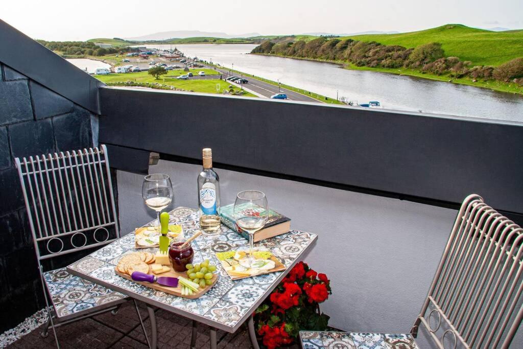 a table with a bottle of wine and glasses on a balcony at Ocean View Penthouse, The Harbour Mill, Westport in Westport