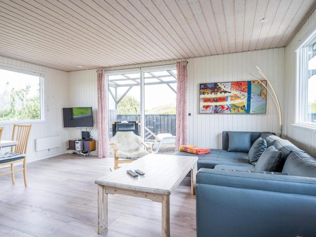 a living room with a blue couch and a table at Holiday home Hvide Sande LXIX in Havrvig
